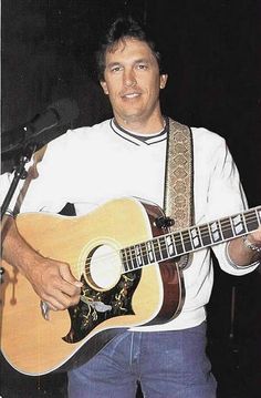 a man holding a guitar in front of a microphone