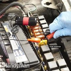 someone is working on an electronic device in their car's engine bay, with the wires attached to it