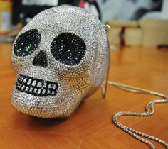 a silver and black skull purse sitting on top of a wooden table