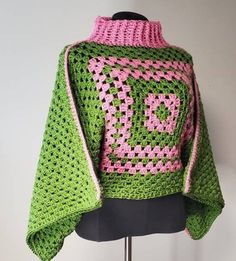 a green and pink crocheted sweater sitting on top of a mannequin