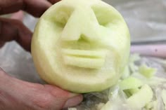 a person holding a piece of fruit with a face carved into it's side