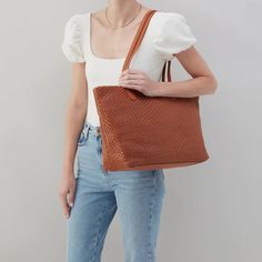 Designed for everyday living, this tote bag has a top zip closure and leather double straps. This tote holds a ton, plus the woven design adds beautiful texture and style to your everyday. View entire Hobo collection 18.5" W X 12" H X 5" D Sandlewood Lining Interior Front: 2 slip pockets, pen pocket & lanyard clip; Interior Back: Horizontal tech zip pocket (12" W x 9" H), 2 slip pockets & pen pocket Exterior Side: D-ring; Exterior Back: Signature phone pocket Fits a 15" laptop Brushed Antique Br Textured Travel Tote Shoulder Bag, Textured Tote Shoulder Bag For Travel, Rectangular Textured Shoulder Bag For Travel, Chic Textured Travel Bag, Everyday Textured Shoulder Bag, Textured Hobo Shoulder Bag For Daily Use, Trendy Textured Tote Shoulder Bag, Woven Leather Hobo Tote Bag For On-the-go, Casual Textured Bags For Everyday Use