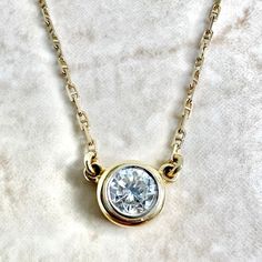 A spectacular vintage 14 karat yellow and white gold solitaire pendant necklace featuring a 5.25 mm natural round diamond weighing approximately 0.60 carat. It is G-H in color and VS2 in clarity. The necklace is 15 inches long. The bezel is 7.50 mm in diameter. The chain is 1.25 mm thick and equipped with a safety snap tab. Weighs 3.42 grams. Stamped 14K. Birthstone: April. Condition: Very good. Light scratches and wear throughout metal. - 14 day return policy, no questions asked. - Free insured Classic 14k Yellow Gold Solitaire Necklace, Classic Solitaire Necklace With Bezel Setting, Classic Yellow Gold Solitaire Diamond Necklace, Classic Round Cut Diamond Necklace With Bezel Setting, Timeless Yellow Gold Solitaire Necklace With Round Stone, Classic Pendant Diamond Necklace With Bezel Setting, Classic Solitaire Pendant Necklace With Bezel Setting, Classic Diamond Necklace With Bezel Setting, Classic Bezel Set Round Diamond Necklace