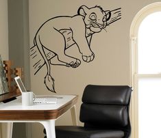 a drawing of a lion is on the wall next to a chair and computer desk