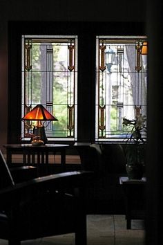 two stained glass windows in a dark room with a lamp on the table next to them