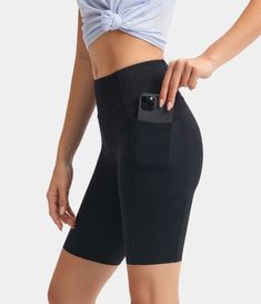 a woman in black shorts is holding her cell phone and showing off the back pocket