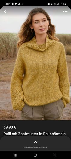 a woman standing in front of a field wearing a yellow sweater and khaki pants