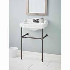 a white sink sitting under a mirror on top of a bathroom counter next to a trash can