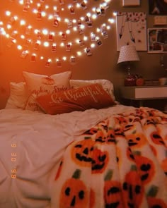 a bedroom decorated with lights and pumpkins on the headboard, bedding, and pillows