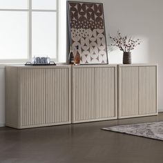 a white sideboard with two vases sitting on top of it next to a window