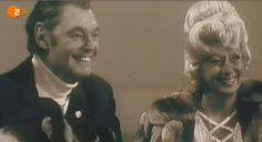 an old photo of two people smiling for the camera, one is wearing a fur coat