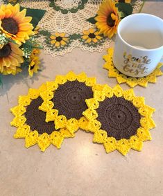 three crocheted coasters on a table next to a coffee cup and sunflowers