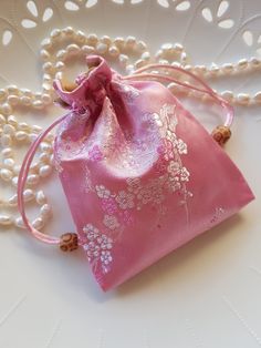 a pink bag with white flowers on it and pearls around the edges is sitting on a table