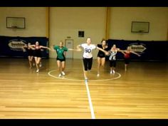 a group of young women standing on top of a basketball court holding hands in the air