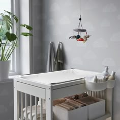 a baby crib in the corner of a room next to a potted plant