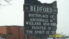 a sign that is on the side of a road in front of some buildings and cars