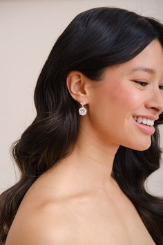 a woman with long black hair wearing a pair of earrings and smiling at the camera