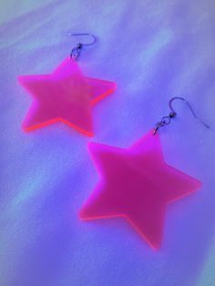 Fluorescent Pink Star EarringsChoice of sterling silver .925 or surgical stainless steel(These earrings pictured are made with surgical stainless steel)Approximately 1.5" wide, and 2.5" long from top of metal hookThese awesome hot pink stars are UV reactive that glow real nice when in the black light. They are still hot pink while not near a black light, please check out the pictures for reference! Bring out the inner retro star in you! :)This product is made to order, colors may appear slightly Trendy Luminous Jewelry For Gifts, Trendy Pink Star-shaped Jewelry, Pink Star Earrings For Party, Pink Star-shaped Jewelry For Party, Pink Star-shaped Party Earrings, Handmade Pink Star-shaped Jewelry, Silver Rave Jewelry For Gift, Tropical 2000s, Lesbian Earrings