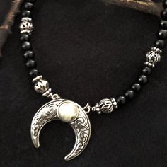 NEW! Inspired by the layers of necklaces worn by our witchy sisters we created an adjustable length beaded beauty we hope you love. Genuine obsidian beads strung with antiqued silver ornate beads and a detailed crescent moon holding a genuine moonstone. Brass based with silver plating. Length can adjust from 17 1/2" to 30". No two moonstones will be alike. COMING SOON! Expected to ship by mid October Orders over $50 ship for free within the USA. All orders usually ship within 24 hours from the U Obsidian Jewelry, Coven, Bead Stringing, Moon Stone, Moonstone, Antique Silver, Beaded Necklace, Charm Bracelet, Plating