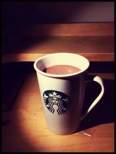 a cup of coffee sitting on top of a wooden table