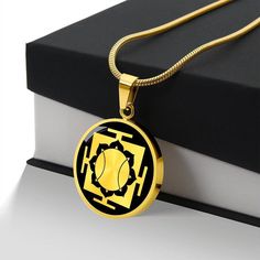 a gold necklace with a black and yellow design on it next to a stack of books