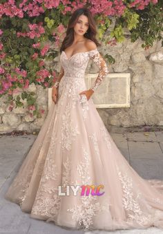 a woman in a wedding dress posing for the camera with pink flowers on her wall