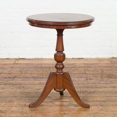 an old wooden table with two legs and a round top, on a wood floor