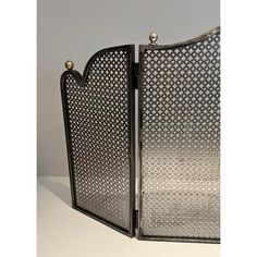 an ornately designed metal fireplace screen on a white table