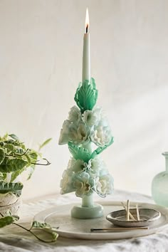 a candle that is on top of a plate next to some plants and vases