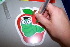 a person holding a pen and writing on a sticker with an apple in the background