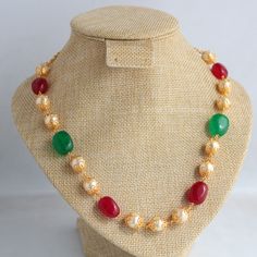 Explore the charm of this exquisite gold-plated necklace featuring captivating red and green semi-precious stones, complemented by semi-cultured pearls. The traditional shape of gold beads, reminiscent of South Indian and Maharashtrian jewelry, enhances the necklace's allure. Handcrafted with care, this 18-inch beauty is a fusion of sophistication and tradition. Pearl Necklace With Gemstone Beads For Festivals And Gifts, Festive Pearl Necklace With Gemstone Beads For Gifting, Festive Gold Necklace With Colorful Beads, Red Beaded Temple Necklace Gift, Red Temple Necklace With Round Beads As Gift, Red Pearl Necklace Gift For Festive Occasions, Red Pearl Necklace For Festive Gift, Red Temple Necklace With Round Beads For Gift, Traditional Pearl Necklaces With Colorful Beads