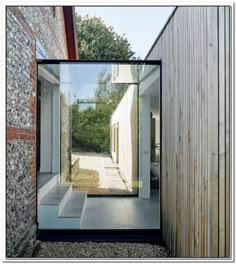 an open door leading to a house with a brick wall and gravel ground in front of it