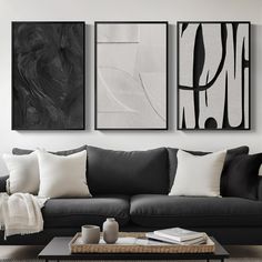 three black and white paintings hang above a couch