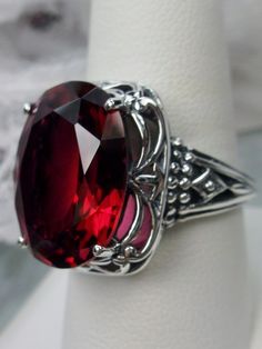 Art Deco Red Ruby Sterling Silver RingRetro Swirl Design#D119 Unlock the mysteries of the past and add a hint of vintage glamour to your jewelry wardrobe with Retro Swirl Ring. Constructed from 925 sterling silver, its intricate filigree swirls create an eye-catching Art Deco-inspired design – perfect for those looking to make a contemporary statement. Featuring a generously sized 18mm x 13mm Red Ruby gemstone in its prong setting, this ring sits 3/4" north south on your finger and 10mm off the Formal Oval Ruby Ring, Elegant Large Stone Ruby Ring Gift, Victorian Oval Ruby Ring For Formal Occasions, Elegant Ruby Ring With Large Stone For Gift, Silver Oval Ruby Ring In Art Deco Style, Elegant Red Cabochon Ruby Ring, Vintage Red Cabochon Ruby Ring, Antique Oval Red Ruby Ring, Victorian Red Oval Cabochon Jewelry