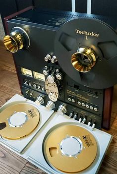 two reels sitting next to each other on top of a wooden floor in front of a stereo