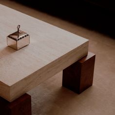 a wooden table with a small silver object on it's top, sitting on the floor