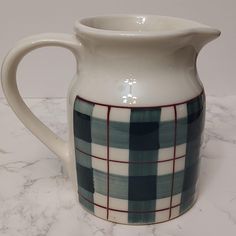 a white and blue plaid pitcher sitting on top of a marble countertop next to a wall