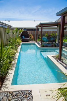 an empty swimming pool in the middle of a backyard with rocks and plants around it