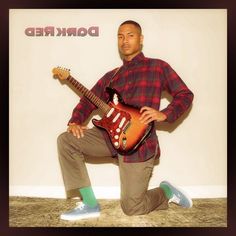 a man sitting on the ground with a guitar in his hand and wearing green socks