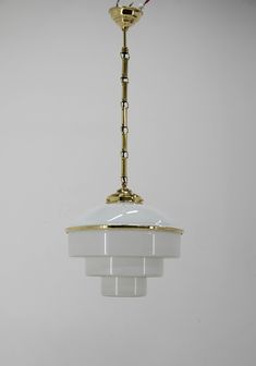 a white and gold light hanging from a ceiling fixture with a red cord attached to it