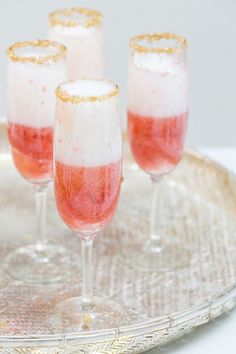 three glasses filled with liquid sitting on top of a metal tray next to each other