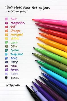 several different colored pens lined up on top of each other in front of a sheet of paper