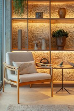 a chair and table in front of a glass wall with potted plants on it