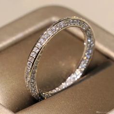 a diamond wedding ring sitting on top of a gold cell phone case with its reflection in it