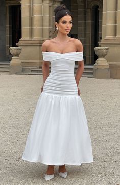 a woman in a white dress posing for the camera with her hands on her hips