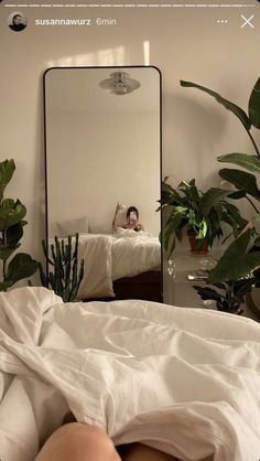 a person taking a selfie in front of a mirror on a bed with white sheets