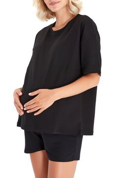 a pregnant woman wearing black shorts and a t - shirt with her hands on her stomach