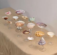 a table topped with wine glasses and seashells on top of a cloth covered table