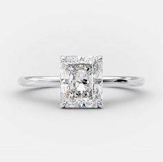 an engagement ring with a cushion cut diamond in the center, on a white background