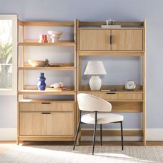 a white chair sitting in front of a wooden book shelf filled with books and vases